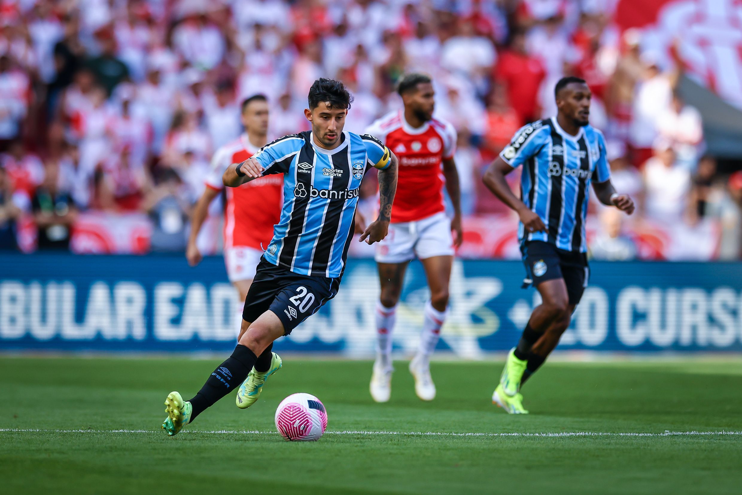 jogadore do grêmio e do internacional em campo, por disputa de bola