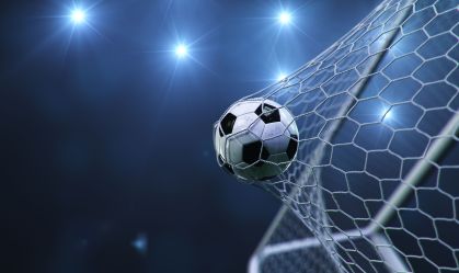 Soccer ball flew into the goal. Soccer ball bends the net, against the background of flashes of light. Soccer ball in goal net on blue background. A moment of delight. 3D illustration