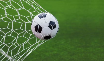 soccer ball in goal with green backgroung