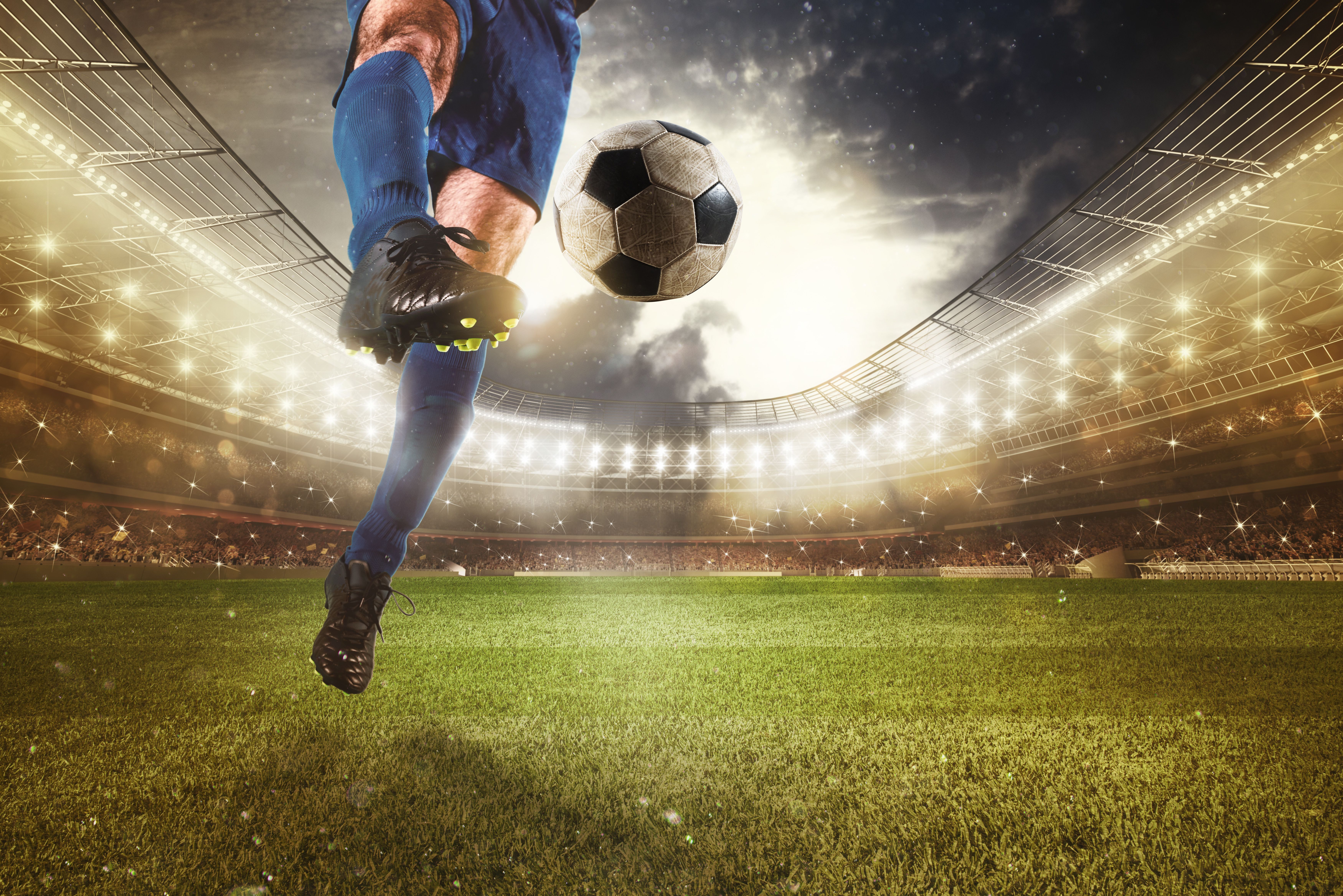 Close up of a striker who kicks the ball to make goals at the stadium during a soccer game