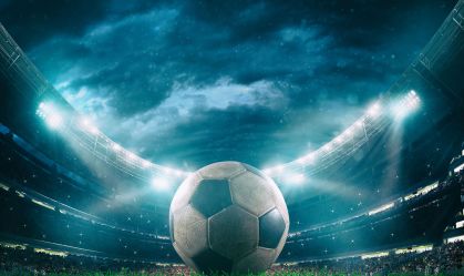 Close up of a soccer ball in the center of the stadium illuminated by the headlights