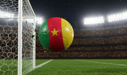 Cameroonian pride a soccer ball bursts through the net stadium lights ablaze