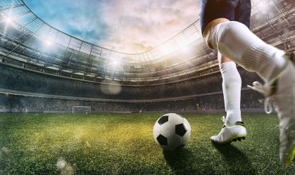 Football scene at the stadium with close up of a soccer shoe kicking the ball