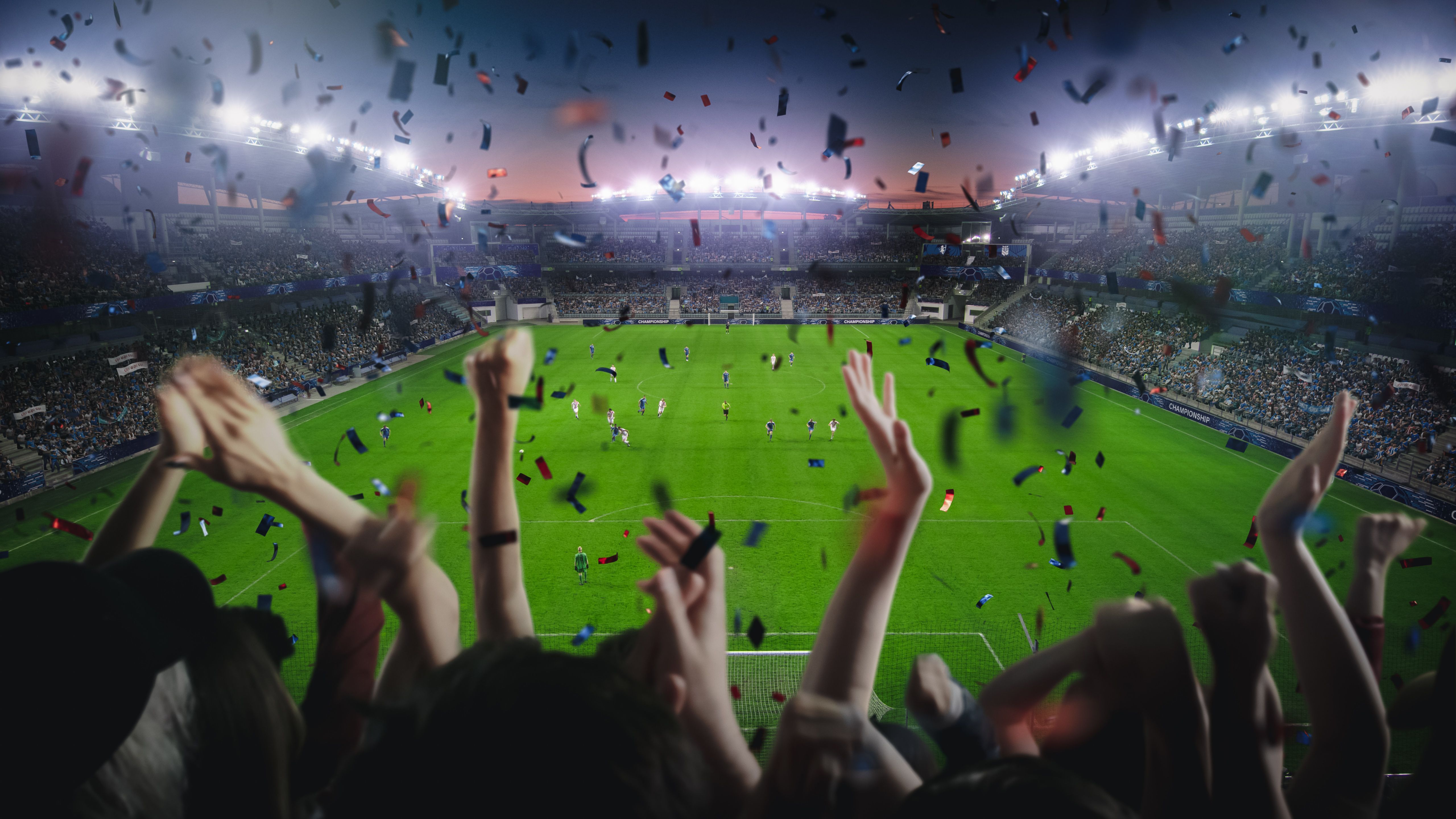 Establishing Shot of Fans Cheer for Their Team on a Stadium During Soccer Championship. Team Scores Goal, Crowd of Fans Celebrate Victory Happily with Confetti. Football Cup Tournament Live.