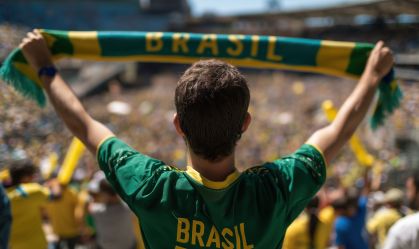 Soccer fan in Brasil jersey holds scarf at football world cup stadium