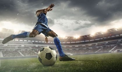 Football or soccer player in action on stadium with flashlights, kicking ball for winning goal, wide angle