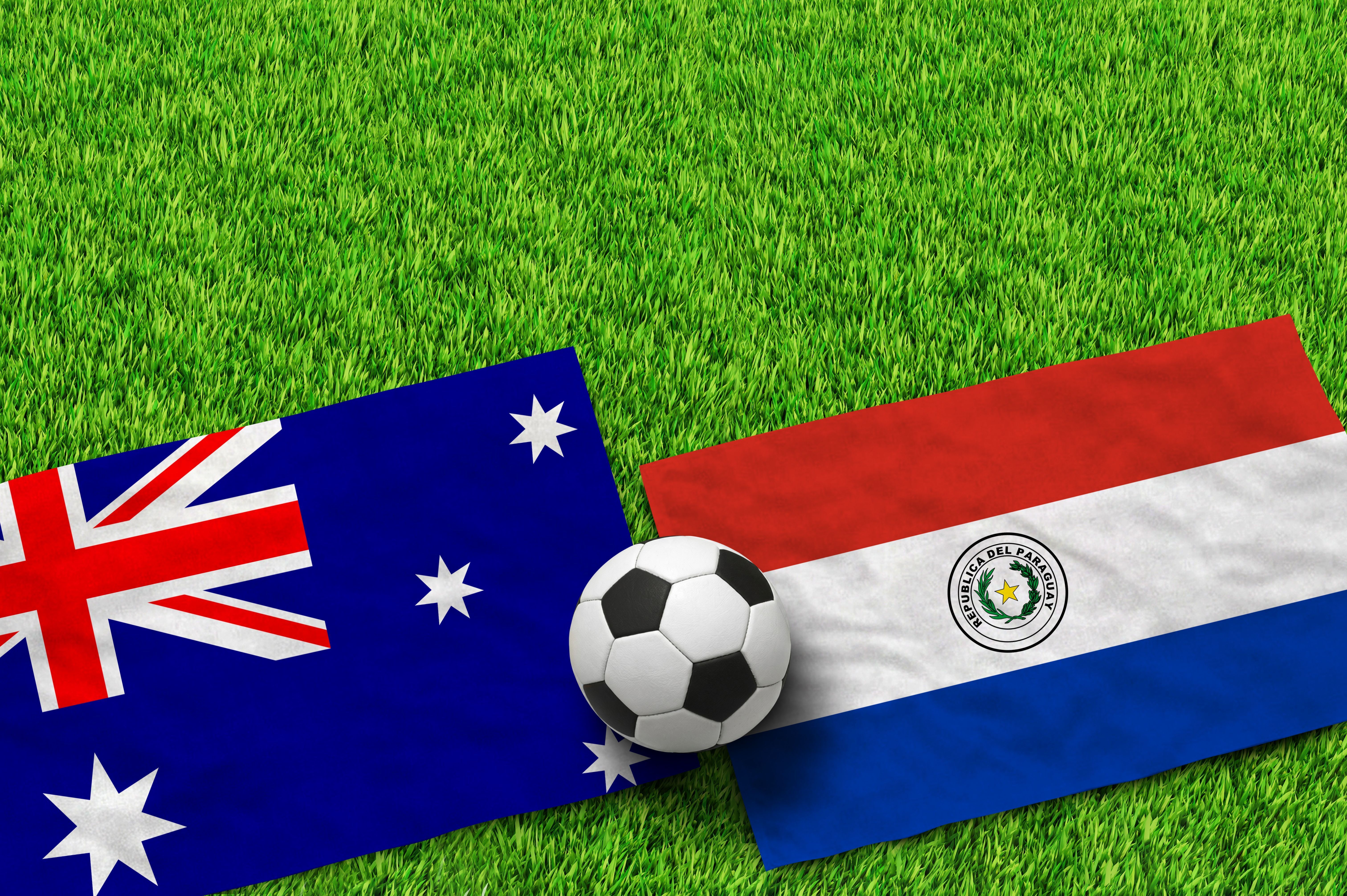 Australian and Paraguayan flags with a soccer ball on green grass field