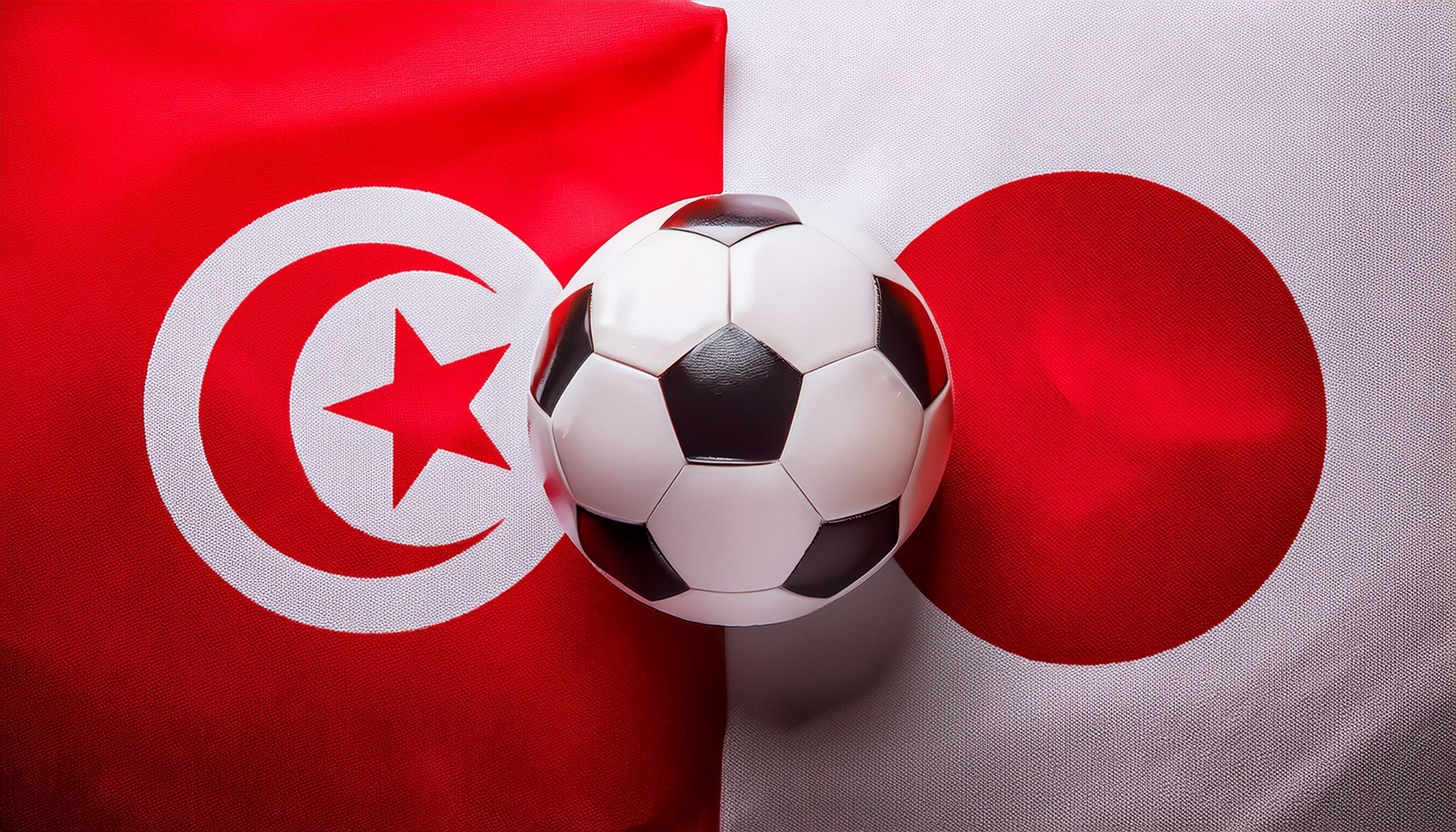 soccer ball between Tunisia flag and Japan flag