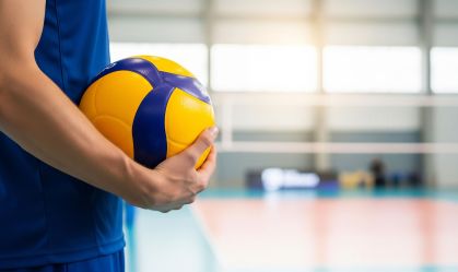 Male volleyball player holding a ball on an indoor court, ready to serve or play